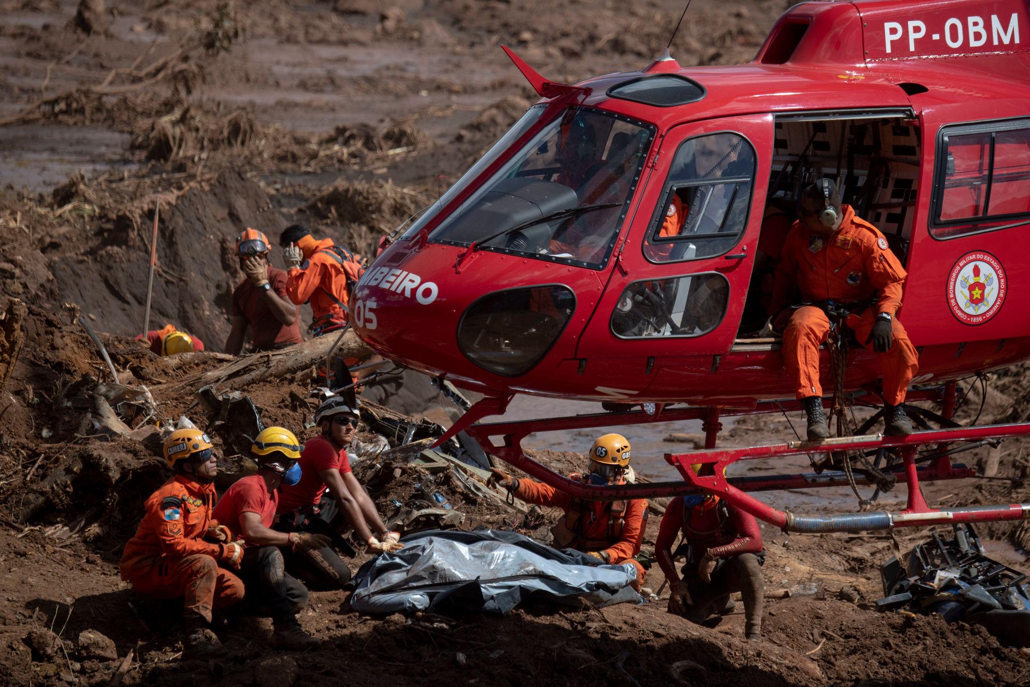 Rescue workers and a Polícia Rodoviária Federal helicopter at the Brumadinho tailings dam collapse site, January 2019